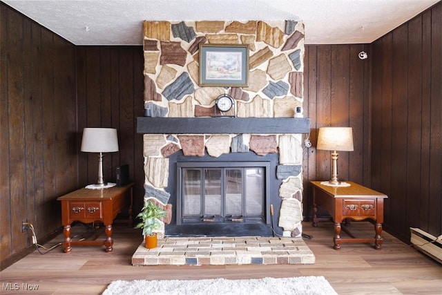 961 Slater Rd, Salem, OH 44460 - detailed view of a fireplace, a baseboard heating unit, wood walls, a textured ceiling, and wood finished floors