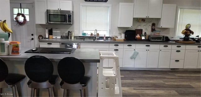 29928 Buck Rd, Salem, OH 44460 - kitchen with appliances with stainless steel finishes, white cabinets, a kitchen bar, dark countertops, and dark wood-style floors