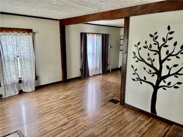 391 Cornell St, Akron, OH 44310 - empty room featuring plenty of natural light, wood finished floors, a textured ceiling, beam ceiling, and crown molding
