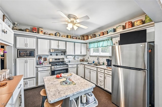 4477 S Warwick Dr, Canfield, OH 44406 - kitchen with stainless steel appliances, under cabinet range hood, a ceiling fan, dark carpet, and a kitchen bar