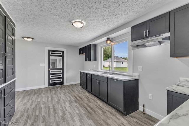 13050 Diagonal Rd, Salem, OH 44460 - kitchen featuring under cabinet range hood, light wood-style floors, a textured ceiling, and dark cabinetry