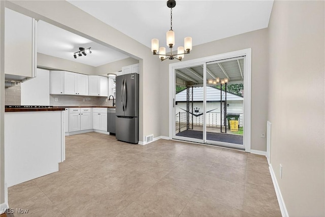 738 Sterling Rd, Wickliffe, OH 44092 - kitchen featuring appliances with stainless steel finishes, a chandelier, white cabinetry, pendant lighting, and dark countertops