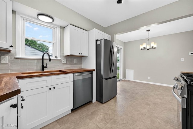 738 Sterling Rd, Wickliffe, OH 44092 - kitchen with butcher block countertops, appliances with stainless steel finishes, backsplash, and a chandelier
