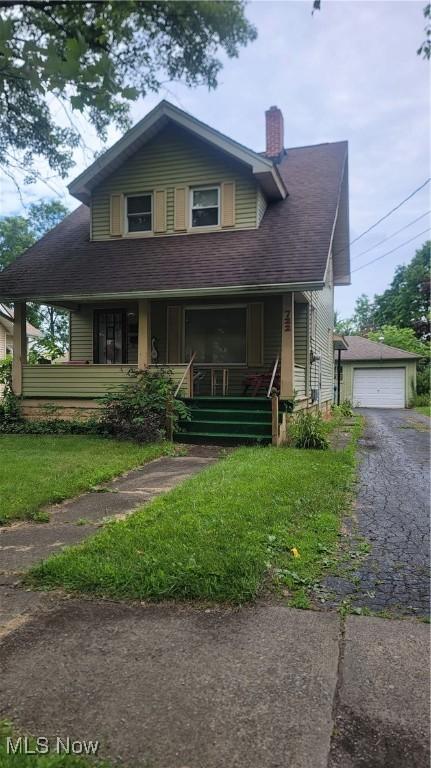 722 5th St, Struthers, OH 44471 - view of front facade with covered porch, a chimney, a front lawn, and a detached garage