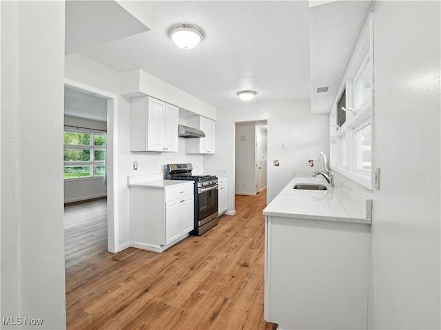 4833 Middle Ridge Rd, Perry, OH 44081 - kitchen with stainless steel range with gas cooktop, light countertops, white cabinets, light wood-style flooring, and wall chimney range hood