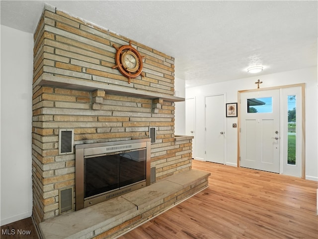 4833 Middle Ridge Rd, Perry, OH 44081 - entrance foyer featuring a brick fireplace, a textured ceiling, and wood finished floors