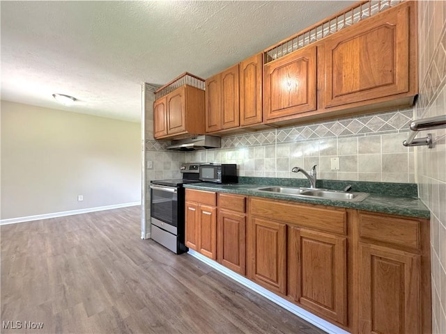 24525 Sherborne Rd, Bedford Heights, OH 44146 - kitchen with stainless steel range with electric cooktop, under cabinet range hood, brown cabinets, black microwave, and a textured ceiling