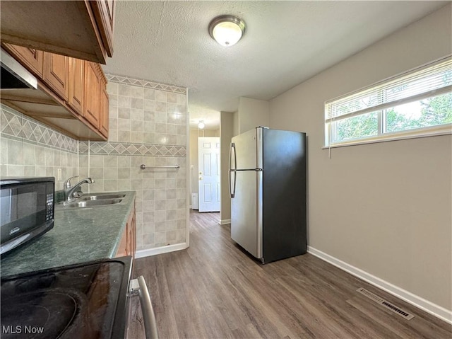 24525 Sherborne Rd, Bedford Heights, OH 44146 - kitchen with freestanding refrigerator, black microwave, dark wood-style floors, brown cabinetry, and dark countertops