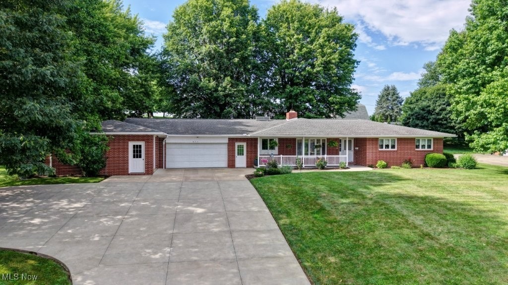 621 Hickory Dr SW, Sugarcreek, OH 44681 - single story home featuring a porch, an attached garage, brick siding, a front yard, and driveway
