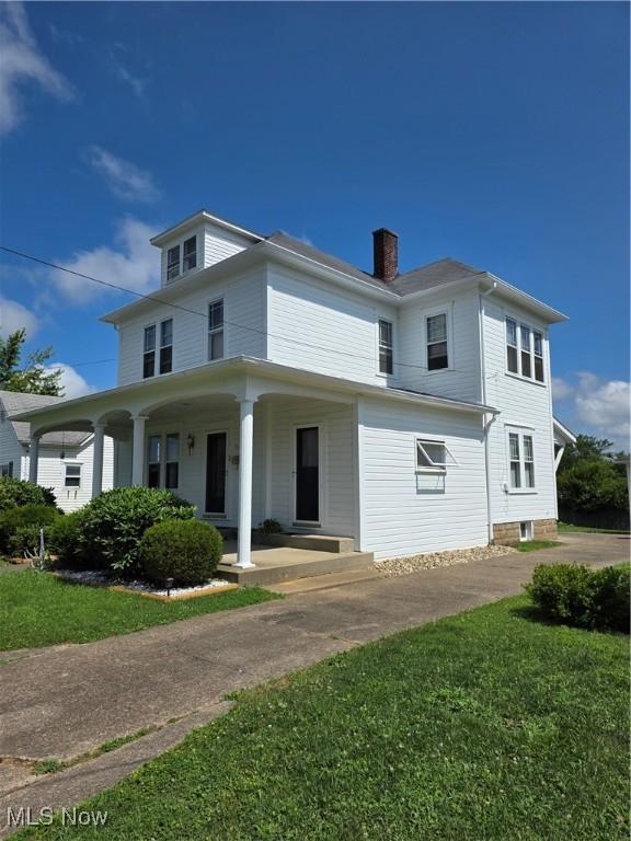 302 High St, Woodsfield, OH 43793 - view of front facade featuring covered porch, a chimney, and a front lawn