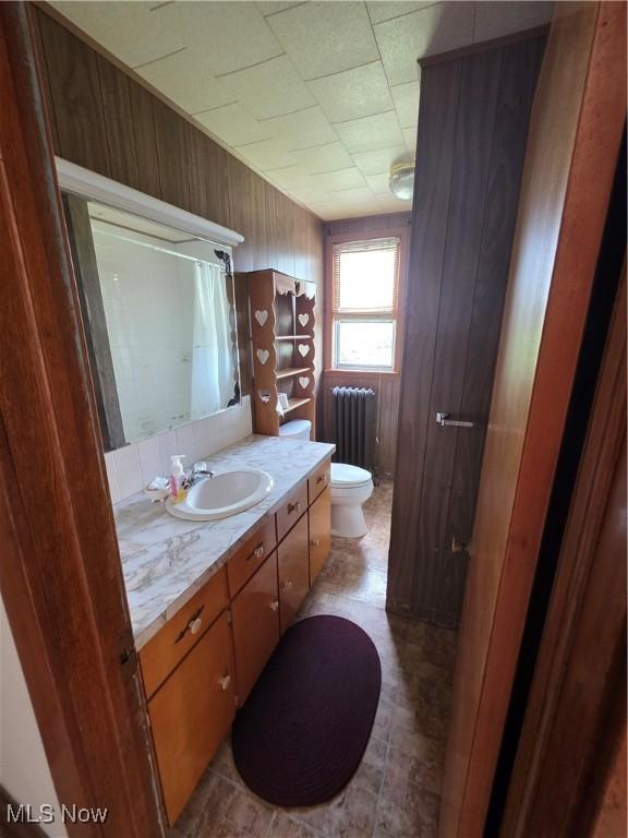 302 High St, Woodsfield, OH 43793 - bathroom with radiator heating unit, vanity, wooden walls, and a shower with curtain