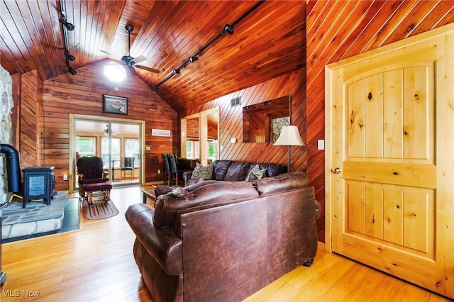 7235 Spillway Rd, Lisbon, OH 44408 - living area with ceiling fan, a wood stove, vaulted ceiling, rail lighting, and wooden walls