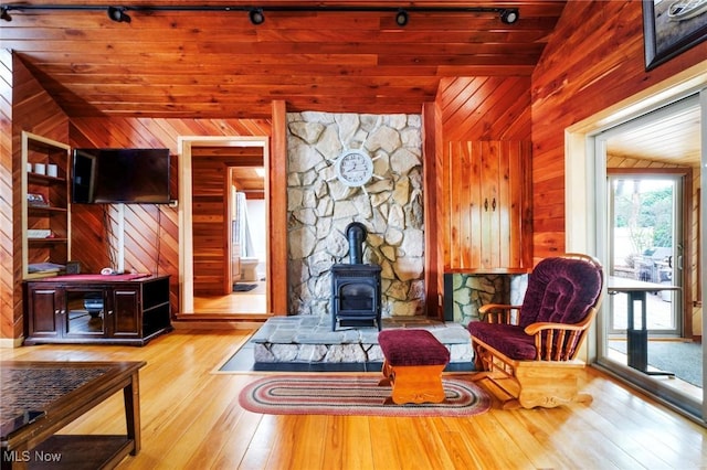 7235 Spillway Rd, Lisbon, OH 44408 - sitting room featuring a wood stove, vaulted ceiling, wood walls, wood-type flooring, and track lighting