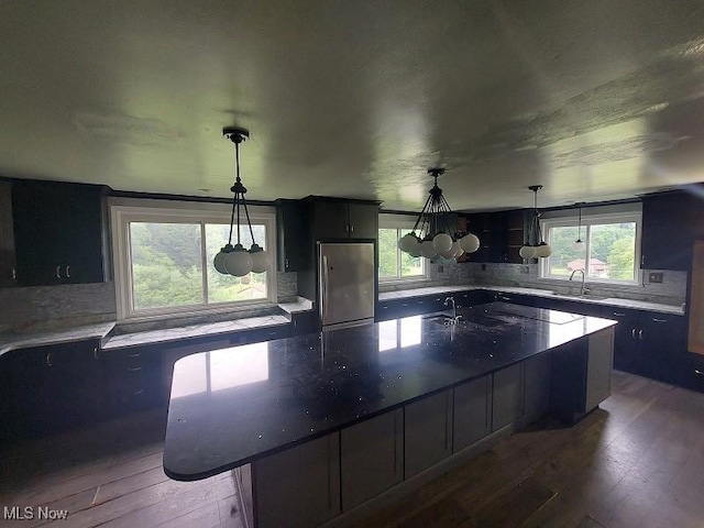 4985 State Route 213, Toronto, OH 43964 - kitchen featuring freestanding refrigerator, backsplash, hardwood / wood-style flooring, a large island, and decorative light fixtures
