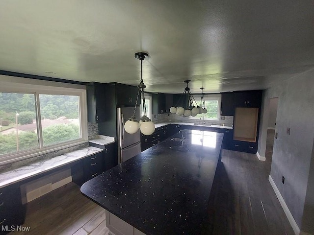 4985 State Route 213, Toronto, OH 43964 - kitchen with freestanding refrigerator, wood finished floors, dark cabinetry, a center island, and tasteful backsplash