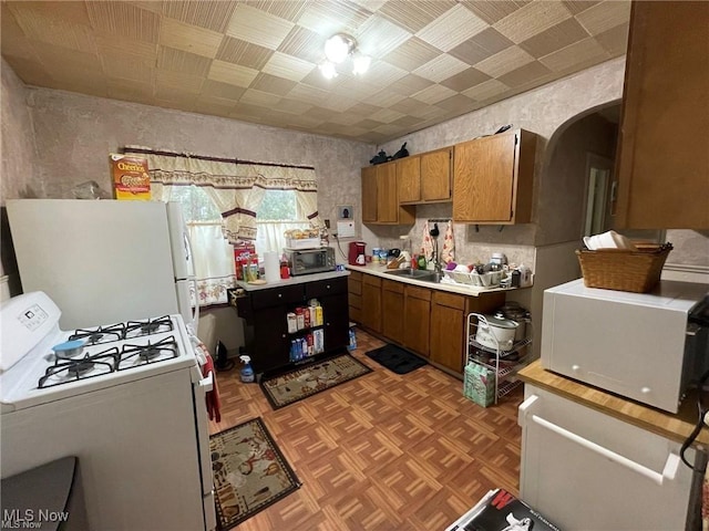 20520 Ball Ave, Euclid, OH 44123 - kitchen with white appliances, brown cabinets, arched walkways, and light countertops