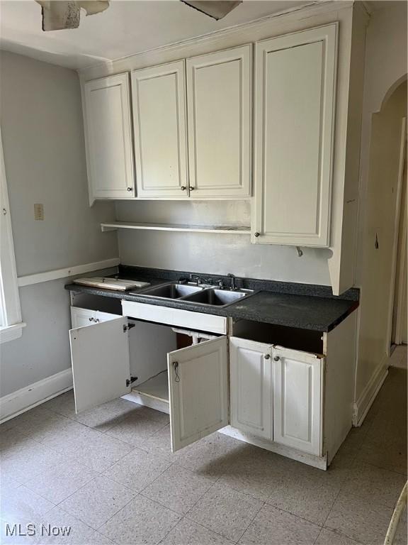 20520 Ball Ave, Euclid, OH 44123 - kitchen featuring dark countertops, arched walkways, and white cabinetry