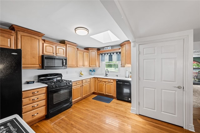 34765 Roberts Rd, Eastlake, OH 44095 - kitchen featuring black appliances, a skylight, light wood-style floors, and light countertops
