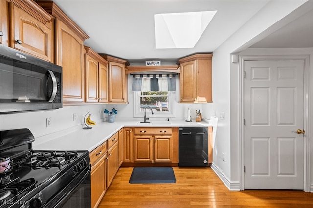 34765 Roberts Rd, Eastlake, OH 44095 - kitchen featuring black appliances, a skylight, light wood finished floors, and light countertops