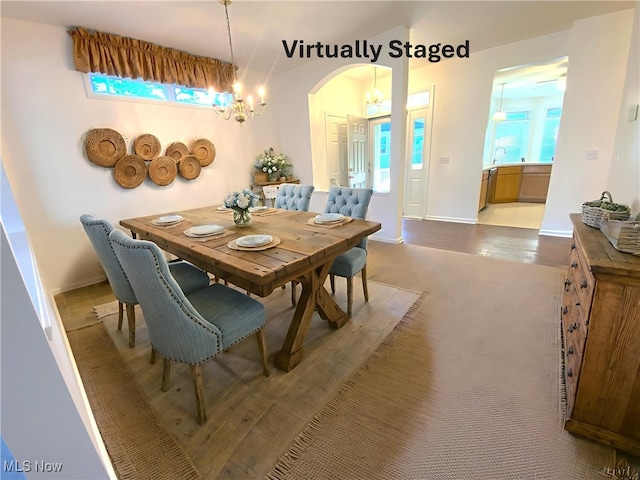 10517 W Ravine View Ct, North Royalton, OH 44133 - dining area featuring a chandelier, arched walkways, and wood finished floors