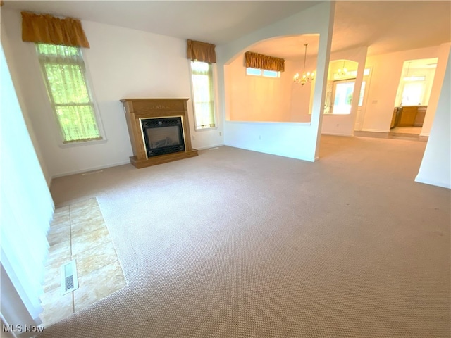 10517 W Ravine View Ct, North Royalton, OH 44133 - unfurnished living room featuring a chandelier, carpet, a glass covered fireplace, and arched walkways