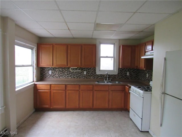 3298 E 143rd St, Cleveland, OH 44120 - kitchen with white appliances, under cabinet range hood, backsplash, brown cabinets, and a paneled ceiling