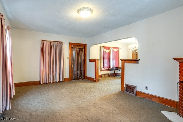516 Floyd St, Akron, OH 44310 - empty room with a chandelier, carpet flooring, a textured ceiling, and arched walkways