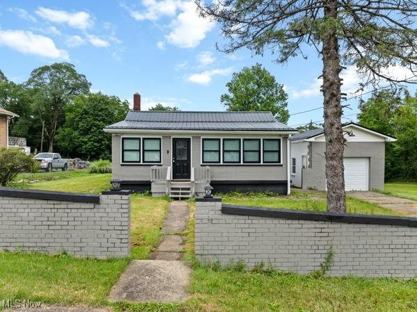345 Ritchie Ave, Weirton, WV 26062 - view of front facade featuring a chimney, an outbuilding, a garage, a front lawn, and a metal roof