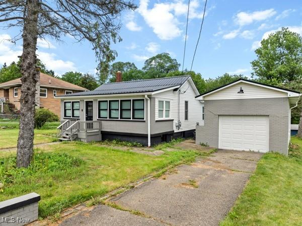 345 Ritchie Ave, Weirton, WV 26062 - view of front facade featuring a chimney, a garage, asphalt driveway, a front lawn, and an outdoor structure