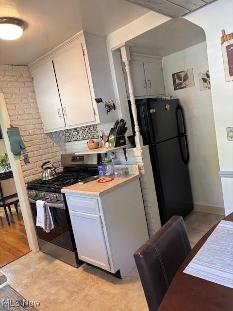 1129 Avondale Rd, South Euclid, OH 44121 - kitchen with gas stove, freestanding refrigerator, light countertops, backsplash, and white cabinetry