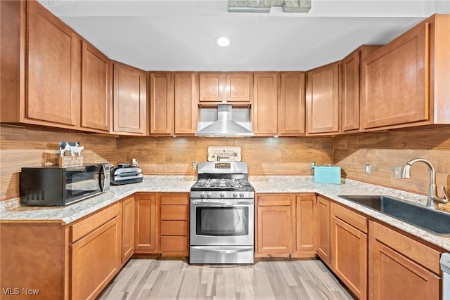 208 Clark St, Berea, OH 44017 - kitchen with stainless steel gas range, wall chimney range hood, black microwave, light wood-style flooring, and decorative backsplash