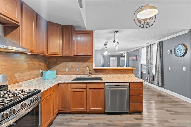 208 Clark St, Berea, OH 44017 - kitchen with stainless steel appliances, a peninsula, light wood-type flooring, wall chimney exhaust hood, and a textured ceiling