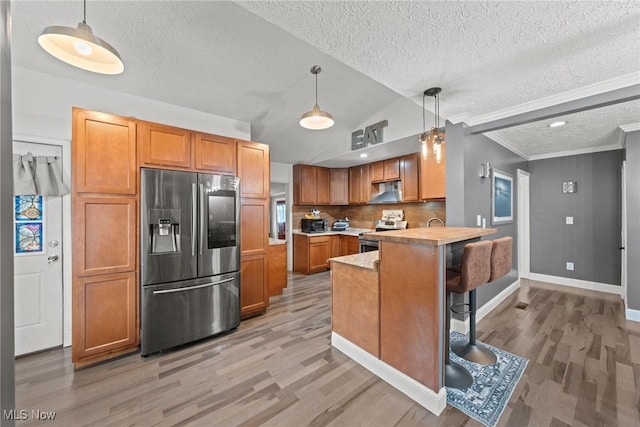 208 Clark St, Berea, OH 44017 - kitchen featuring stainless steel appliances, light wood-style floors, a textured ceiling, a peninsula, and brown cabinets