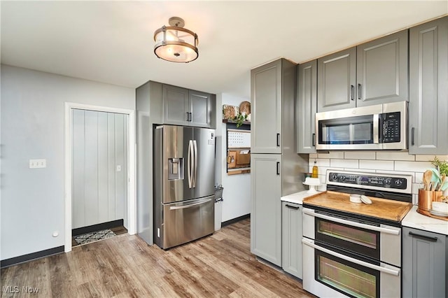 661 Wynne Dr, Coventry, OH 44319 - kitchen featuring stainless steel appliances, gray cabinetry, light wood-style floors, and tasteful backsplash