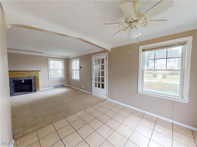 3863 Grosvenor Rd, South Euclid, OH 44118 - unfurnished living room featuring a ceiling fan, a textured ceiling, light carpet, a high end fireplace, and light tile patterned flooring