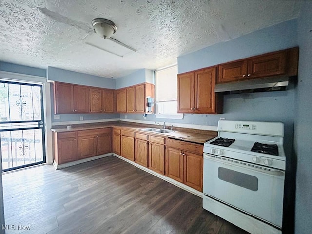 1200 E 125th St, Cleveland, OH 44112 - kitchen featuring white range with gas cooktop, under cabinet range hood, brown cabinetry, dark wood-style floors, and a textured ceiling