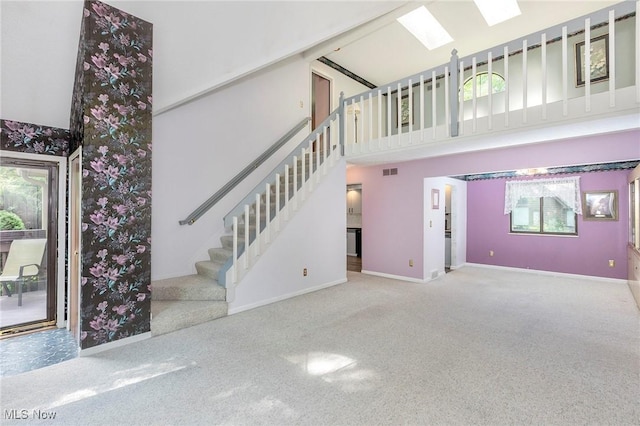 836 Arboretum Cir, Sagamore Hills, OH 44067 - unfurnished living room with plenty of natural light, carpet flooring, a high ceiling, a skylight, and stairs