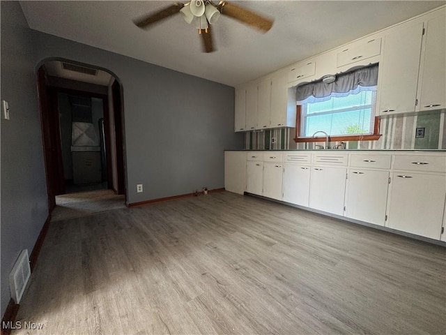 14782 Hametown Rd, Doylestown, OH 44230 - kitchen with light wood-type flooring, ceiling fan, arched walkways, and white cabinetry