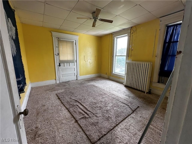 625 Main St, Caldwell, OH 43724 - carpeted empty room featuring radiator, ceiling fan, and a paneled ceiling