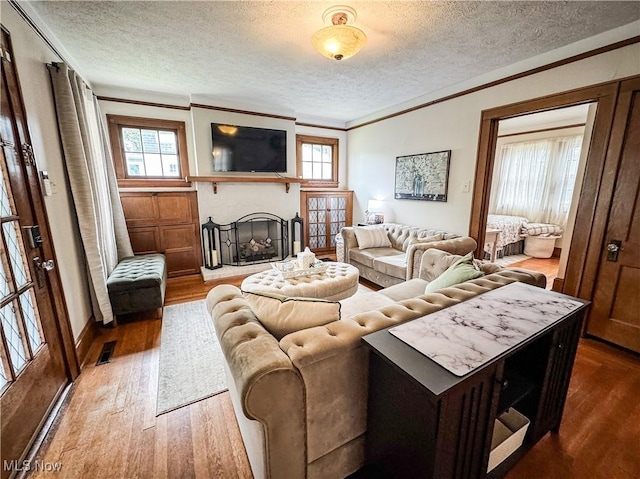 2208 Oak St, Parkersburg, WV 26101 - living room featuring a textured ceiling, wood finished floors, ornamental molding, healthy amount of natural light, and a brick fireplace