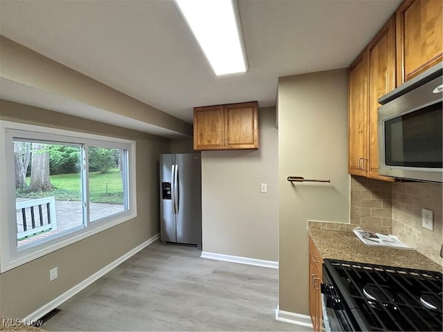 4514 Lilac Rd, South Euclid, OH 44121 - kitchen with stainless steel appliances, brown cabinets, backsplash, light wood finished floors, and light countertops
