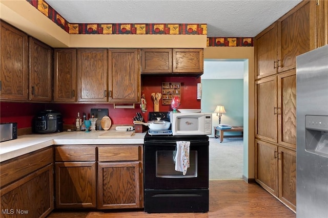 1781 Old Forge Rd, Mogadore, OH 44260 - kitchen featuring black range with electric stovetop, stainless steel fridge, light countertops, a textured ceiling, and light wood finished floors