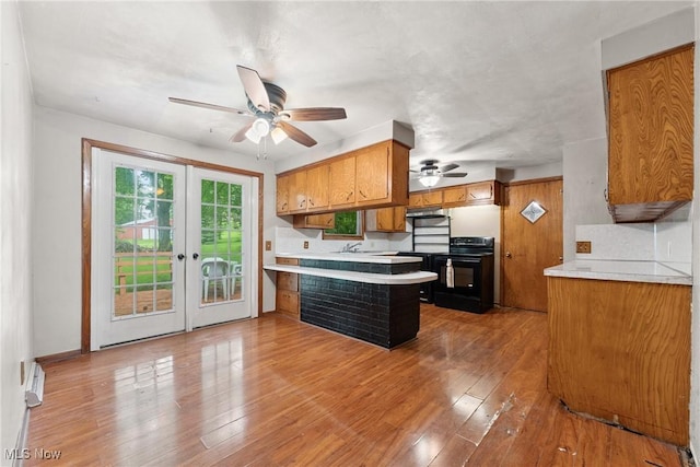4524 Sherer Ave SW, Canton, OH 44706 - kitchen with black range with electric stovetop, a peninsula, brown cabinets, a ceiling fan, and light countertops