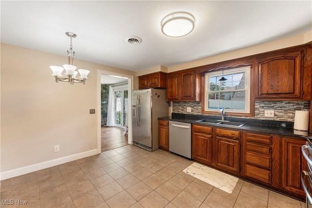 2615 Daffodil St NE, Canton, OH 44705 - kitchen with stainless steel appliances, tasteful backsplash, dark countertops, and a chandelier