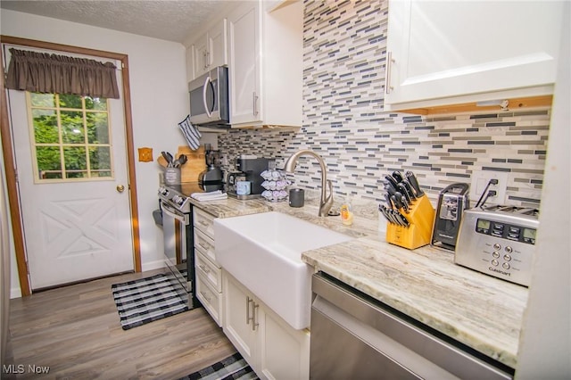 191 Ridgeland Dr, Toronto, OH 43964 - kitchen with appliances with stainless steel finishes, white cabinets, decorative backsplash, wood finished floors, and light stone countertops