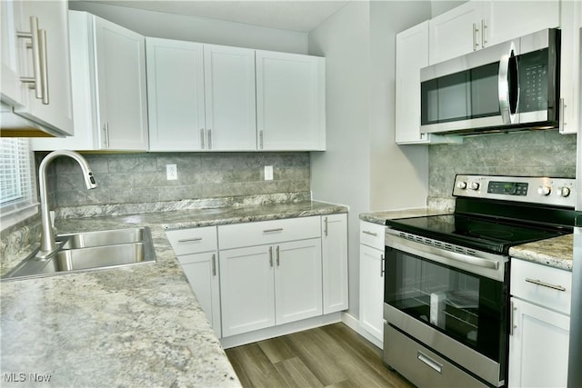 1006 Trumbull Ave, Warren, OH 44420 - kitchen with stainless steel appliances, white cabinets, wood finished floors, decorative backsplash, and light stone countertops