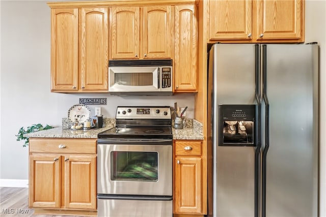 2395 Tremont Ave, Cleveland, OH 44113 - kitchen featuring stainless steel appliances, light stone countertops, light wood-style floors, and light brown cabinets