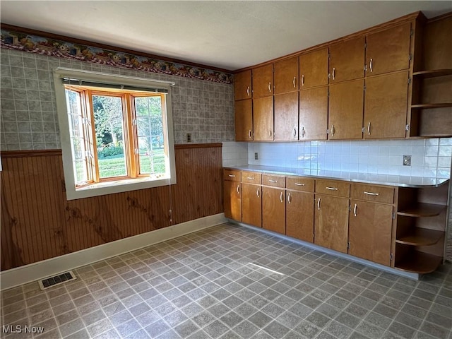 468 Carl St, Cumberland, OH 43732 - kitchen featuring open shelves, light floors, brown cabinetry, light countertops, and a wainscoted wall