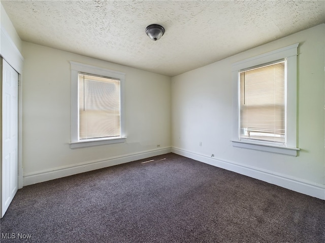 237 E Thornton St, Akron, OH 44311 - empty room featuring dark colored carpet, plenty of natural light, and a textured ceiling