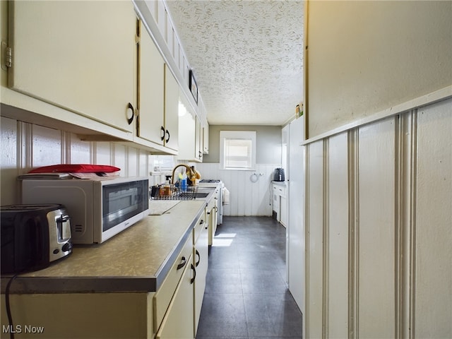 237 E Thornton St, Akron, OH 44311 - kitchen with a textured ceiling, a wainscoted wall, and white cabinets